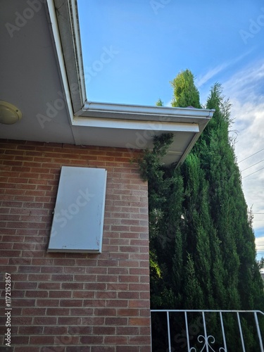 Outdoor Brick Wall with Green Foliage and Blue Sky Background - Urban Nature Scene with Architectural Elements and Natural Beauty