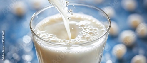 Milk pouring into glass, blurred background photo