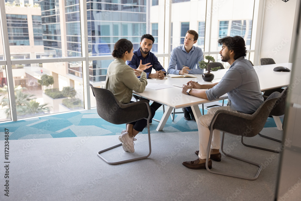 © fizkes - Diverse team of young male colleagues listening to speaking Indian business leader at meeting table in collaboration room interior, talking in contemporary workspace. Candid shot with copy space © fizkes - Diverse team of young male colleagues listening to speaking Indian business leader at meeting table in collaboration room interior, talking in contemporary workspace. Candid shot with copy space