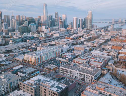 Aerial view of San Francisco's skyline with the Bay Bridge in the background during sunset, showcasing the city's buildings and waterfront.