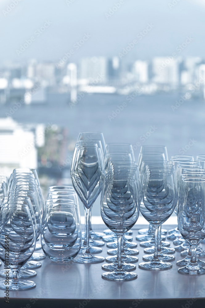 Wine and Drink glasses are arranged in front of drinks counter bar with cityscape background
