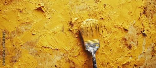 Vibrant yellow paint applied with an old brush on a textured wall emphasizing a DIY home improvement project in progress. photo