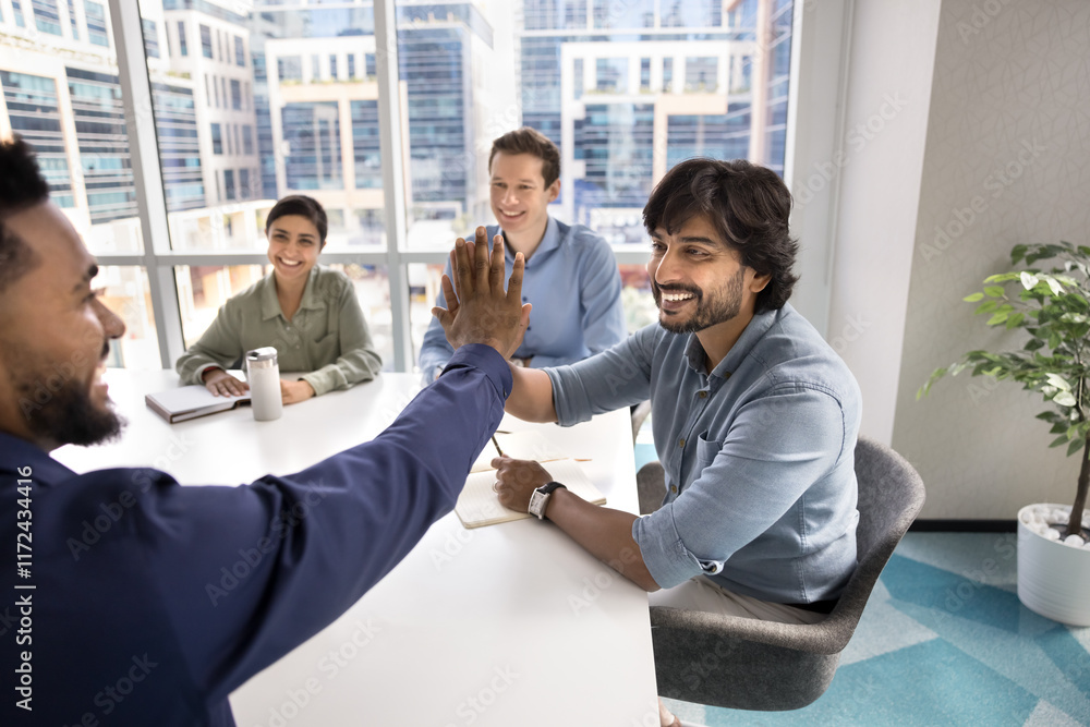 © fizkes - Happy diverse business colleagues making high five gesture at successful meeting, joining hands, smiling, laughing, feeling excited about project success, corporate teamwork, creative brainstorming