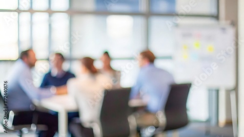 A blurred image of a group in a business meeting, discussing strategies.
