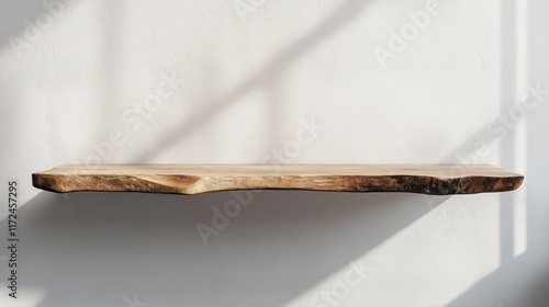 A vintage wooden shelf with uneven edges, set against a plain backdrop in an empty and serene interior setting