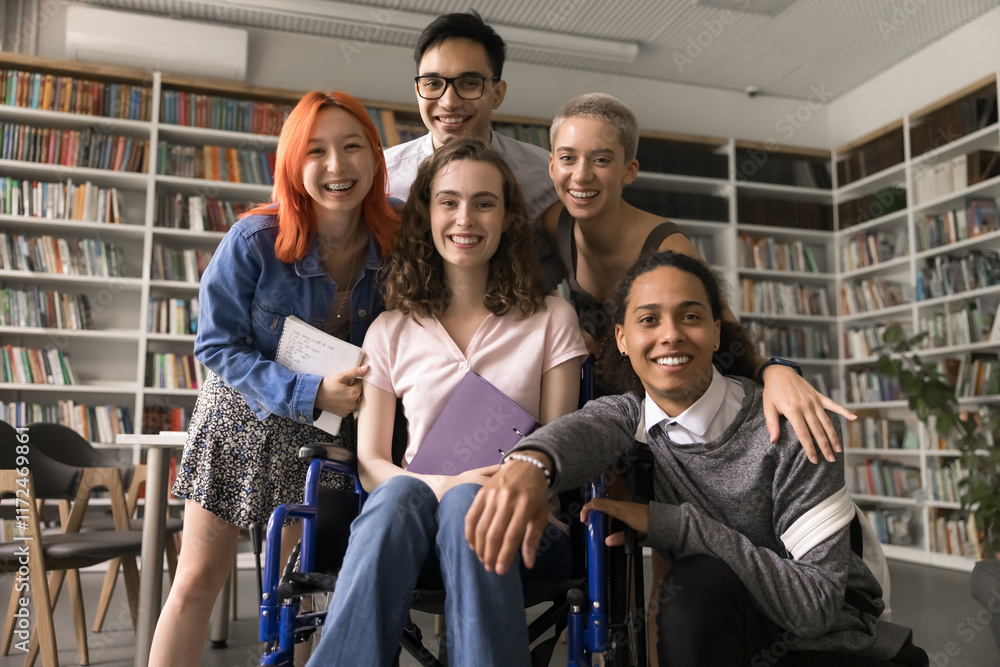 © fizkes - Happy diverse team successful motivated college pupils university students including teenage girl wheelchair user gather in library for group portrait hug laugh enjoy unity bonding friendly relations
