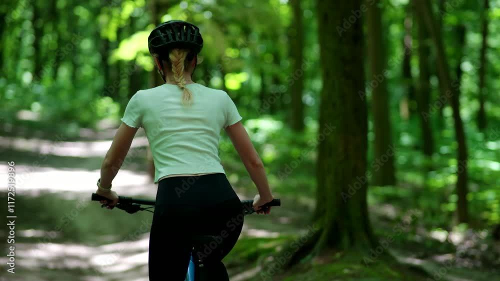 Woman biking outdoors in sunny park wearing helmet and sunglasses	