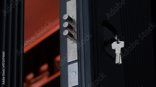 Extended door lock bolts and keys in the keyhole of an open black armored entrance door. Opening the door. Access to the premises. Photo. Selective focus