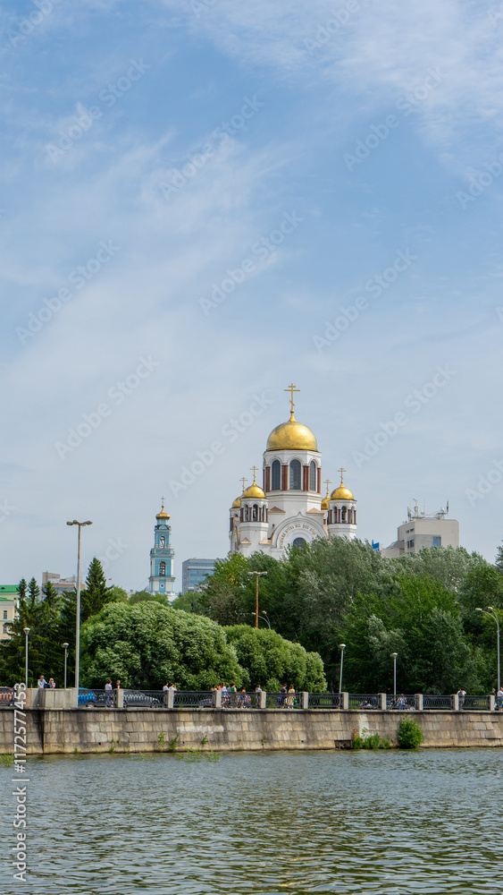 Fototapeta premium Central city pond in Yekaterinburg, Russia. Church on Blood in Honour of All Saints Resplendent in the Russian Land on embankment. Church in honor of Ascension of Lord. Vertical image