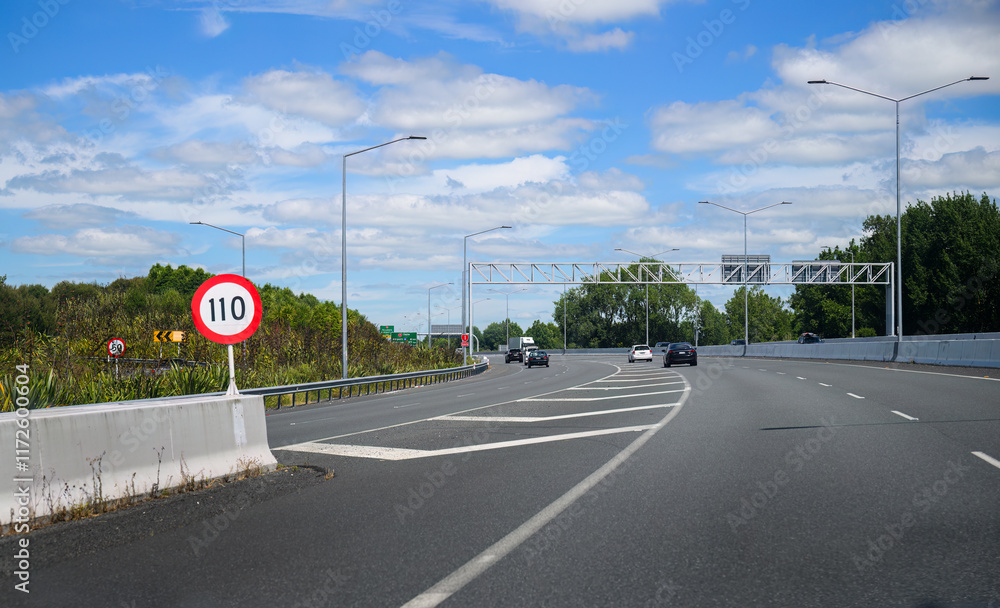 110 km/h road sign at Kapiti Expressway. Cars travelling on the road. New Zealand.