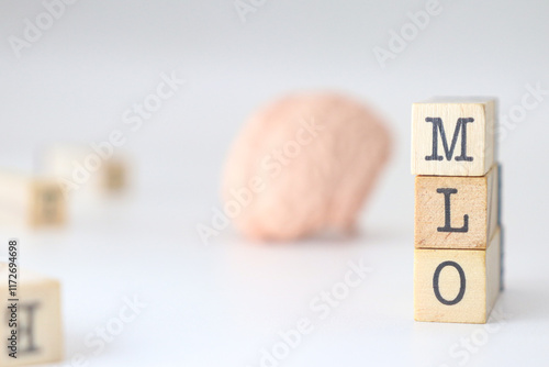 Machine Learning and Optimization acronym. MLO abbreviation written on wooden cubes isolated with a brain on white background with copy space.