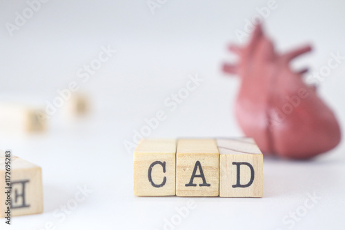 Coronary Artery Disease abbreviaiton. CAD word written on wooden cubes isolated with heart on white background with copy space.  Concept of cardiology illness. photo