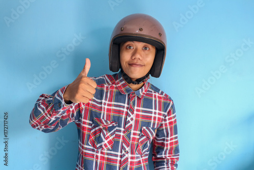 Young Asian man wearing motorbike helmet giving 