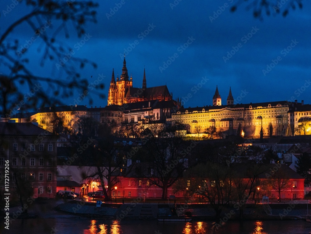 Obraz premium Prague Castle illuminated at night with reflections on the Vltava River.