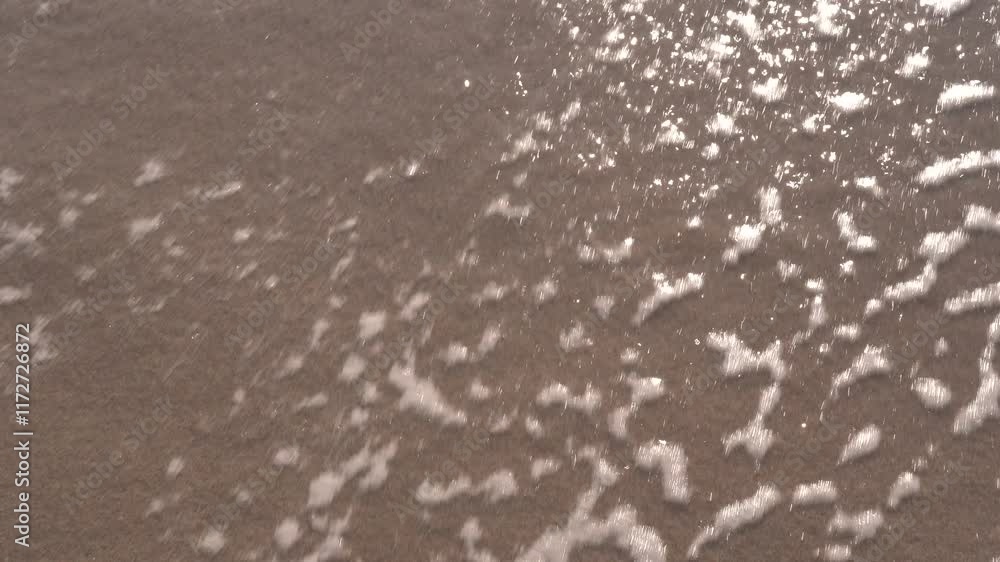 Año 2024 grabado en la arena y una ola de mar borra los números.