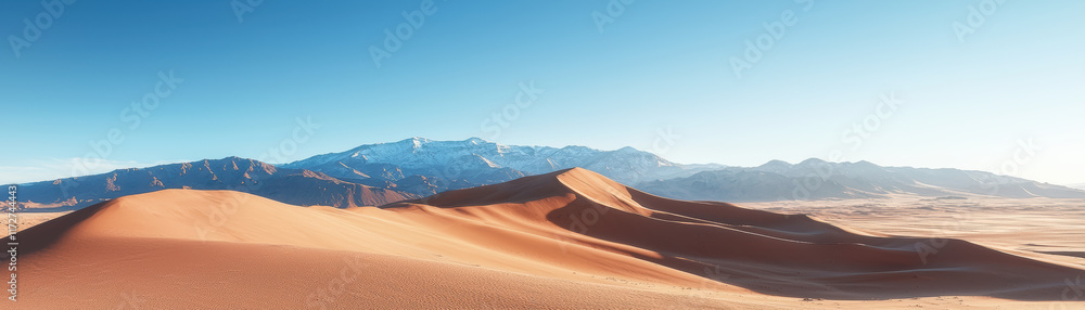 Naklejka premium Majestic mountain range with golden sand dunes under clear blue sky