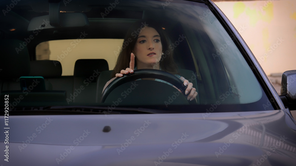 Young woman hesitating and pointing finger up while driving car