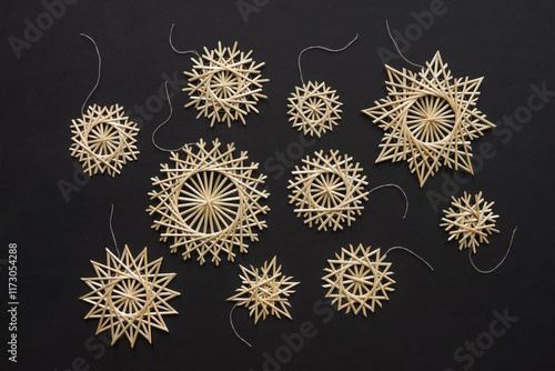 Snowflakes are made of straw on a black background. Christmas decor. Top view. Straw weaving. Lutsk, Ukraine