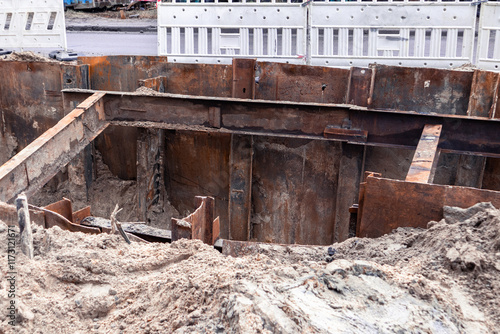 A hole in the ground with iron reinforcements for repairing a pipeline. Repair of pipeline under the roadway photo