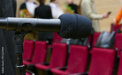 Black microphone in conference room with audience and red seat