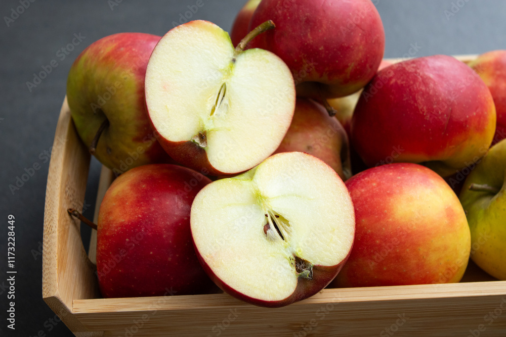 Fresh small organic red apples in a wooden crate on grey table background Fresh small organic red apples in a wooden crate on grey table background