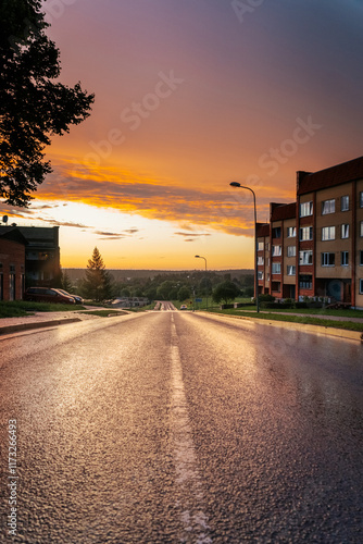 road down the mountain past apartment buildings with an impressive sunset after the rain