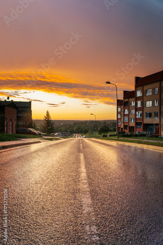 road down the mountain past apartment buildings with an impressive sunset after the rain