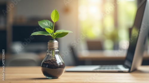 Green Plant Growing in Light Bulb on Desk with Laptop Background photo