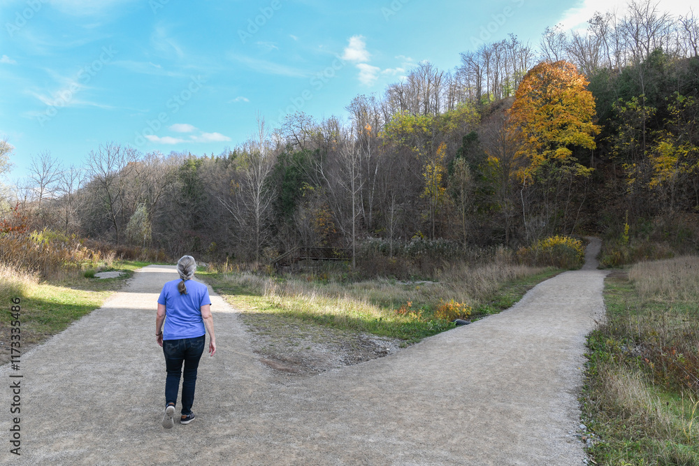 Rear view of a mature woman taking the left fork on a footpath, Ontario, Canada Rear view of a mature woman taking the left fork on a footpath, Ontario, Canada