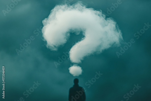 Silhouette of a person under a cloud shaped like a large question mark in a foggy atmosphere photo