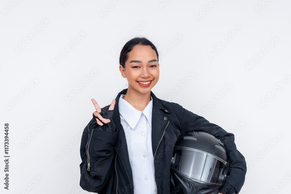 A young female motorcycle delivery driver smiling and making the peace sign while posing with her helmet. Isolated on a white background. A young female motorcycle delivery driver smiling and making the peace sign while posing with her helmet. Isolated on a white background.