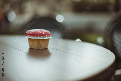 Close-up of a Cupcake on a table with red icing and sprinkles made to look like a mushroom photo