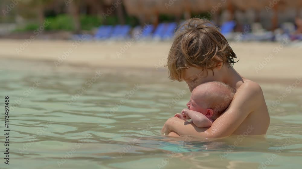 A little boy holds his tiny newborn brother in his hands while sitting in the sea on a sunny beach. A heartwarming moment capturing sibling bonding, family love, and the newborn's first experience in A little boy holds his tiny newborn brother in his hands while sitting in the sea on a sunny beach. A heartwarming moment capturing sibling bonding, family love, and the newborn's first experience in