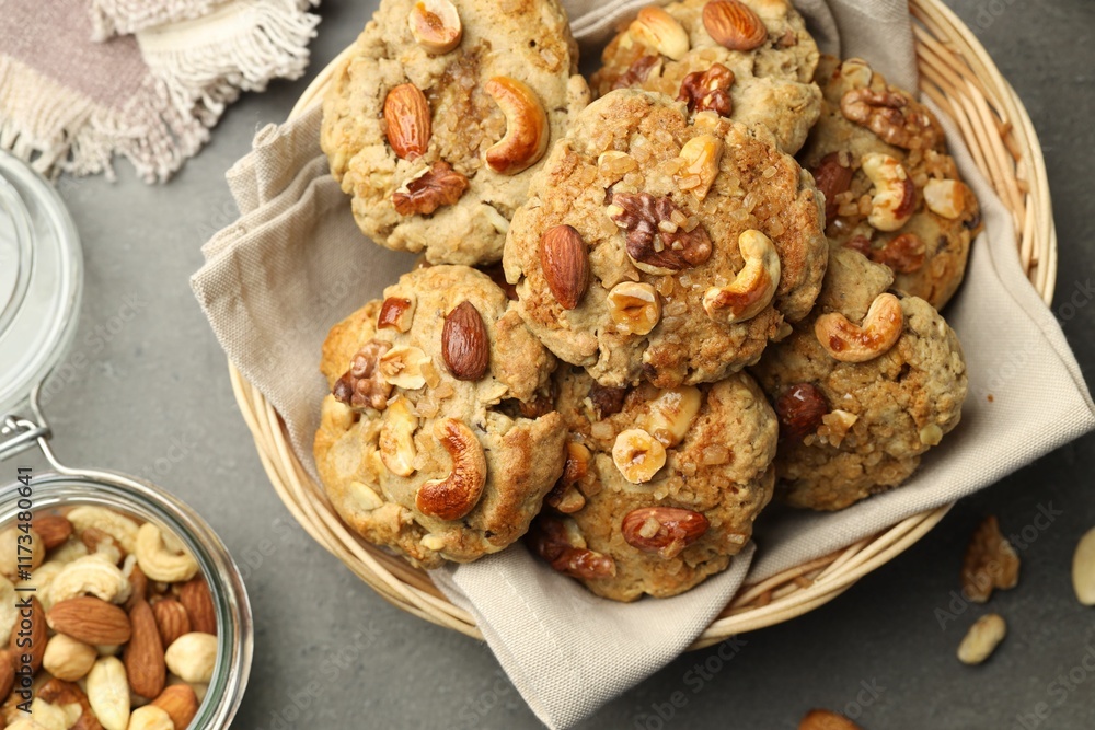 Fototapeta premium Tasty cookies with nuts in wicker basket on grey table, top view
