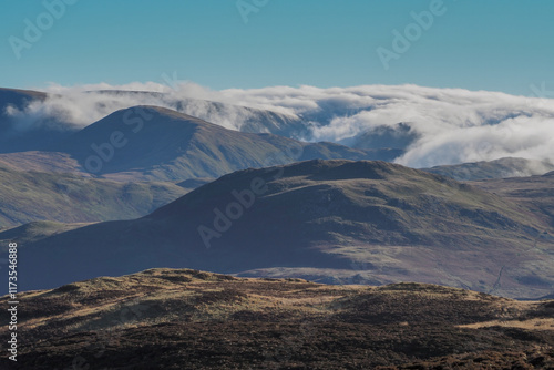 View from the top of Gowbarrow Fell with clouds cascading over the high fells, Lake District, UK photo