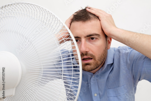 Flushed man feeling hot in front of a fan