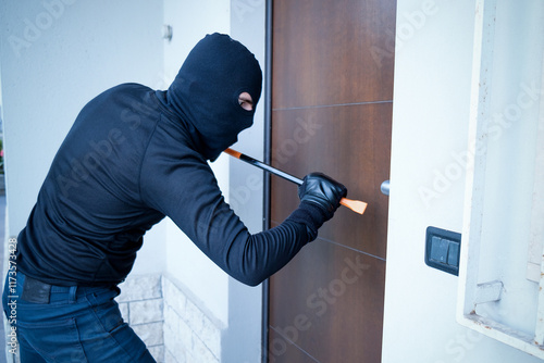 Burglar trying to force a door lock using a crowbar