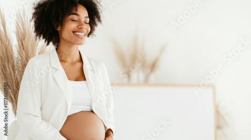 Pregnant woman with afro hairstyle smiling softly indoors, copy space