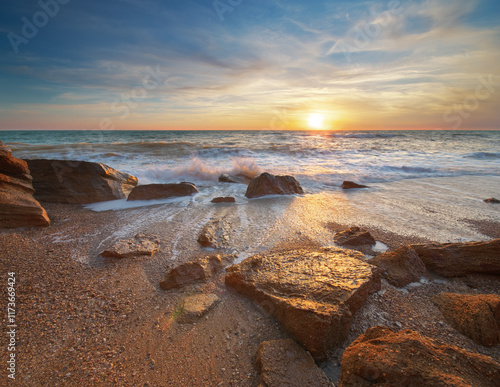 Stones and sea during the sunset. Beach shore among rocks and stones on evening sunset. photo