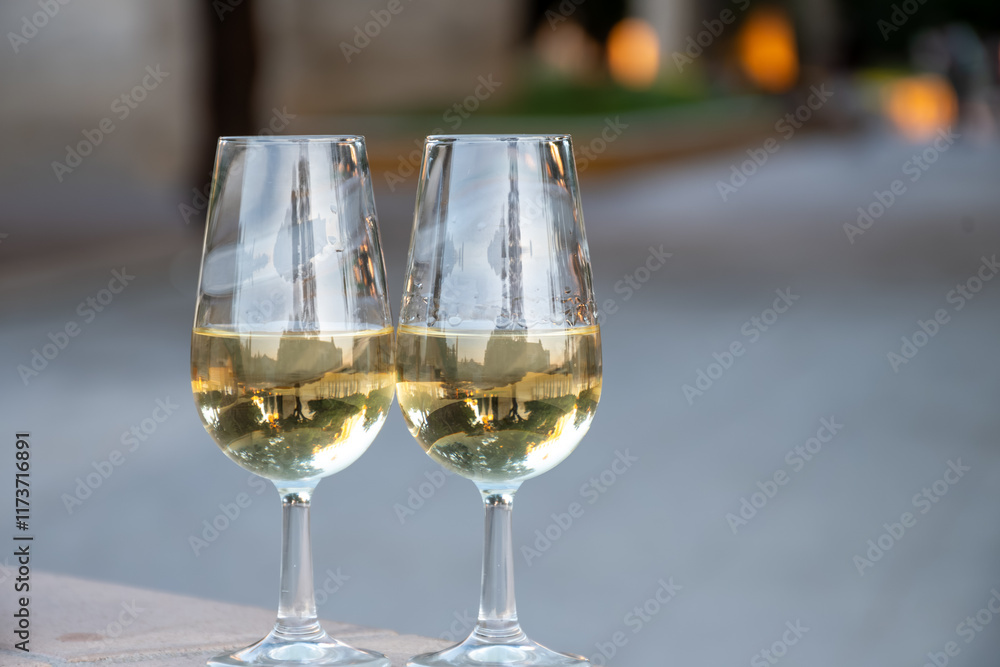 Obraz premium Sherry wine glasses with fino and old bogedas jerez wine cellars on background in Jerez de la Frontera, wine glasses outdoor, cityview, Andalusia, Spain
