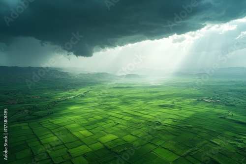 Sunlight breaking through stormy clouds over lush green landscape