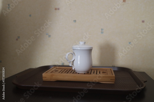 A white chakhai creamer with a handle and lid without a pattern stands on a shepherd's tea board for the tea ceremony photo