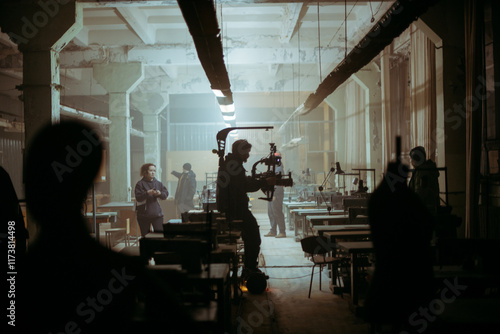 Director of photography with a camera in his hands on the set. Professional videographer at work on filming a movie, commercial or TV series. Filming process indoors, studio