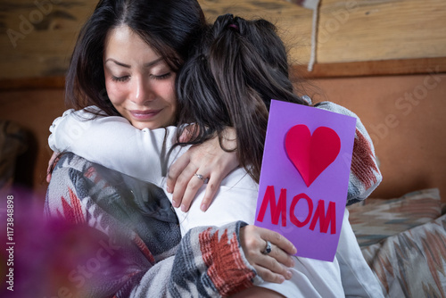 A little girl is iGiving her mother a card that says 