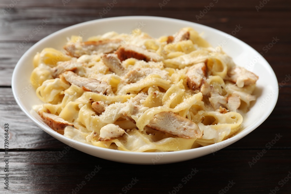 Tasty Alfredo pasta with chicken on wooden table, closeup Tasty Alfredo pasta with chicken on wooden table, closeup