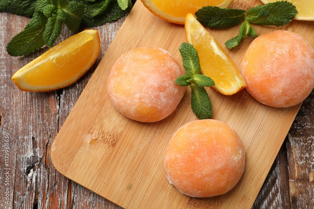 Board with tasty mochi, cut orange and mint on wooden table, flat lay Board with tasty mochi, cut orange and mint on wooden table, flat lay