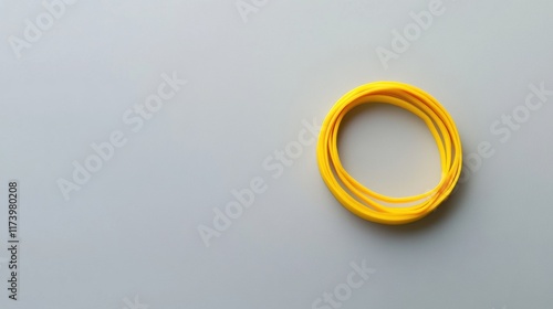 A neat arrangement of bright yellow rubber bands forming overlapping circles on a smooth pale grey surface, emphasizing simplicity, geometry, and vibrant color contrast. photo