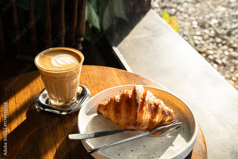 Hot coffee latte with latte art milk foam in cup mug with Croissant on wood desk on top view. As breakfast In a coffee shop at the cafe,during business work concept,vintage style