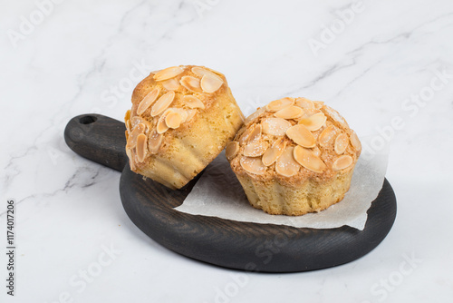 Vegan Small Almond ake with crispy almond petals on top. On a wooden board. White background. Close-up photo