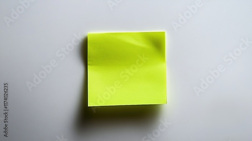 Single neon green sticky note adhered to a smooth white surface, displaying a clean, modern aesthetic with vibrant color and slight texture on the paper. photo